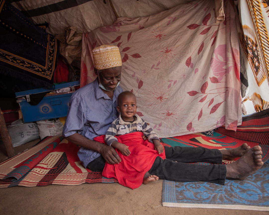 Village elder & pastoralist Omar and son, photographed outside their homestead Mororo location, in Tana River County, where his 19 dependents, including one child with a mental disability, live.