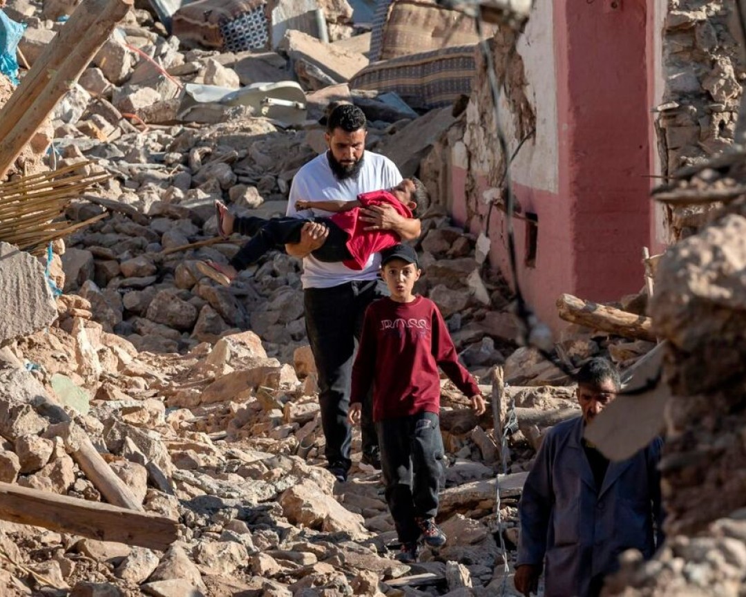 People walk past destroyed houses after an earthquake in the mountain village of Tafeghaghte, southwest of the city of Marrakesh, on September 9, 2023. Moroccos deadliest earthquake in decades has killed more than 1, 300 people, authorities said on September 9, as troops and emergency services scrambled to reach remote mountain villages where casualties are still feared trapped.
