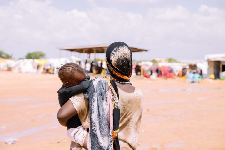 Fatuma Salat Shoro bærer sit barn i Ziwani-lejren for internt fordrevne. Hun blev for nylig fordrevet af de ubarmhjertige oversvømmelser efter kraftige regnskyl i området. El Nino-fænomenet fortsætter med at forårsage voldsomme regnskyl i området, hvilket skader ejendom og forstyrrer livet i lokalsamfundene.