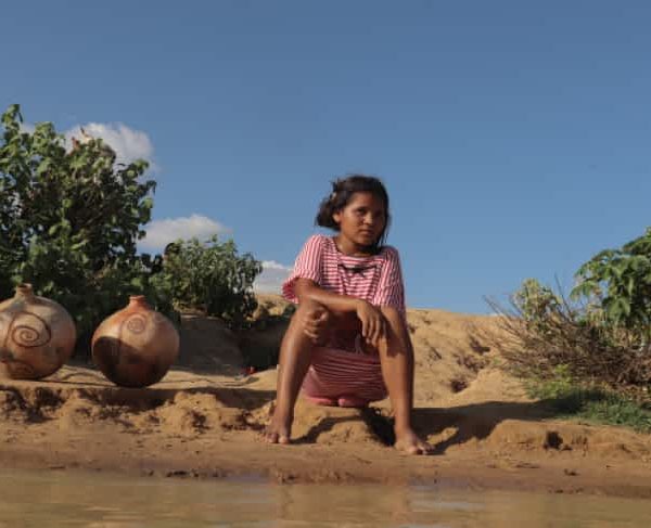 Pige sidder på jorden ved vandkant