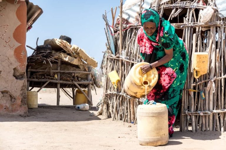 Kvinde hælder vand fra dunk, Kenya 2022