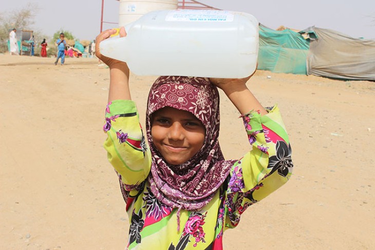Lille pige bærer vanddunk på hovedet, Yemen