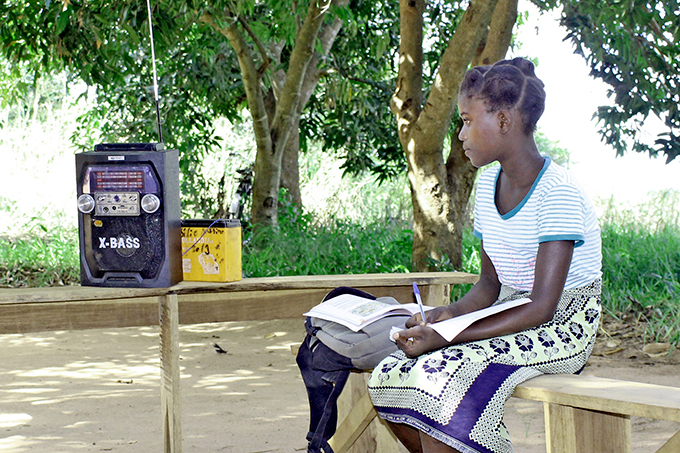 Skolepige lytter til skoleradio i Mozambique